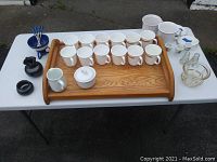 Full view of all items on white table showing arrangement of mugs, bowls, egg cups, fondue set, serving tray and other pieces.
