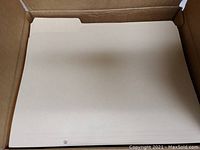 Close-up image of multiple manila file folders stacked inside a box, showing the three-tab design and smooth texture.