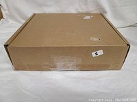 Closed brown cardboard box containing the new AquaSpa shower head and arm set.