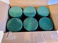 Top view of 6 green-topped Glade air freshener spray cans inside a cardboard box