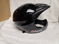 Side view of glossy black Razor youth full face helmet with visor and chin guard, showing Razor logo on chin area.