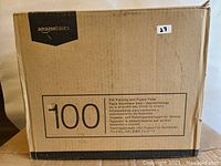 Cardboard box packaging showing Amazonbasics branding and quantity of 100 pads.