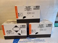 Three unopened boxes of Glade automatic spray air freshener refills showing product code, batch number, and expiration date 2022.