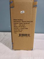 Cardboard box side view showing product label with brand, description, size, SKU, weight, and country of origin.