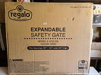 Close-up photo of the cardboard box showing the Regalo brand, model 0723 DS, color gray, and size fitting openings 28 to 42 inches wide and 23 inches high.