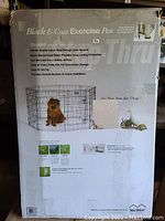 Photo of the box showing the product name, image of a dog inside the pen, and product features including secure latch door, black electro-coat finish, foldable design, ground anchors, and corner stabilizers.