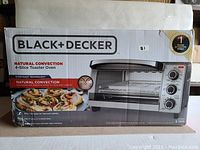 Box of the BLACK+DECKER 4-slice natural convection toaster oven showing branding and product image.