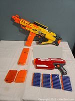 Photo showing Nerf Stampede ECS blaster, red Mega blaster, four orange dart magazines, and multiple foam darts.