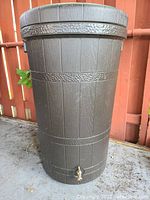 Front view of the rain barrel showing the textured shell, spigot at the base, and overall condition.