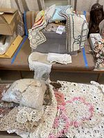 Overview of assorted tatting, crocheted lace linens and table runners, folded and loose.