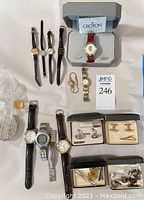 Overview of assorted mens and ladies wristwatches and cufflinks on display including boxed Croton watch.