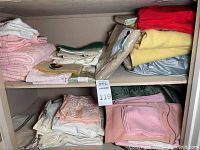 Shelves with pink and white towels, assorted cotton napkins, embroidered linen pieces