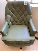 Front view of green tufted swivel armchair with cushioned seat and armrests