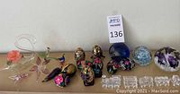 Full display of Joe Rice paperweight, cloisonné and hand-painted eggs, blown glass birds and flowers, clear glass toy train cars, and glass paperweights with floral motifs
