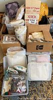 Boxes filled with fabric, batting, craft materials, and light crafting supplies including paper and cords.