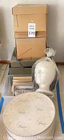 Stacked boxes with a white wig form holding a white wig next to them