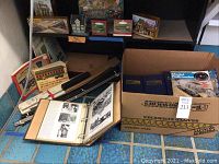 Overview of model train books, magazines in binders, track lengths, box with more magazines.