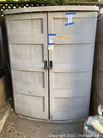 Front view of closed beige resin storage shed with sticker labels on door fronts.