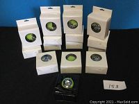 15 Mini Apple Speakers in original packaging with clear windows showing different colored speakers including green and blue. One speaker is out of packaging, displaying its compact circular design.