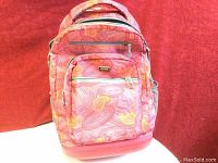 Front view of pink patterned JWorld New York wheeled backpack showing zippered compartments and mesh side pockets.
