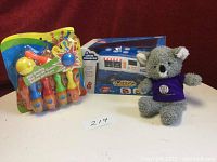 Photo showing all three items: the Little Universe ice cream truck in box, mini bowling set still in packaging, and small stuffed koala on a table with white background