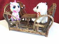 Photo showing 4 Beanie Boos plush toys seated on rustic twig wood picnic table and benches against a red background.
