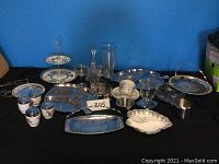 Wide view of the collection showing various serving platters, glassware, metal basket, porcelain cups, and other tableware items.