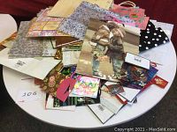 Photo showing a large pile of assorted gift bags on a round white table, including floral, polka dot, and novelty prints.