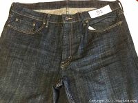 Front view showing the button closure, belt loops, front pockets, coin pocket, and size tag inside the jeans waistband.