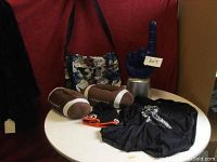 Wide view of lot items on round white table: football slippers, NFL beanie, football jersey, shoulder bag, and foam cheering finger.