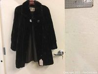 Full front view of the mink coat hanging on a door showing overall condition and length.