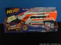 Photo of Nerf Rough Cut 2x4 blaster in original packaging with 8 elite darts and branding visible.