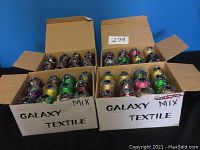 Two open cardboard boxes labeled 'Galaxy Textile Mix' showing multiple spools of brightly colored embroidery thread wrapped in plastic.