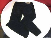Black women's skinny leg corduroy pants laid out flat showing back side