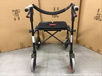Front view of the black Nexus walker showing the padded seat, four wheels, and hand grips with brake levers.