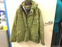 Front view of green Ripzone ski/snowboard jacket with pixelated square pattern hung on hanger