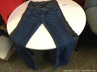 Two pairs of women’s jeans laid out on a circular table, showing front view: one pair dark blue Bongo jeans, one pair black Volcom jeans.