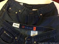 Close-up view of waistbands and tags of two jeans showing sizes and brands: Bluenotes size 29/30 and Buffalo David Bitton size 29/32
