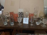 Wide view of all the assorted vintage glasses displayed on a table including various sizes and colors of glasses.