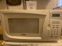 Front and right side view of white Kenmore microwave with mesh window door and control panel.