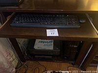 Desk with a slide-out keyboard tray holding keyboard and mouse, Samsung monitor on top, black printer and desktop tower below desk.