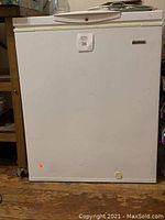 Front exterior of compact white Kenmore deep freezer showing the flat door with no visible major damage.