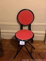 Side front view of black metal framed plant stand with circular red top