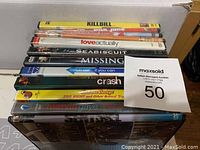 Photo showing a stack of assorted DVDs with visible titles like Kill Bill, Love Actually, Seabiscuit, 4 Missing, Catch Me If You Can, and more.