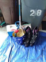 Lot laid out on blue tarp showing lacrosse stick, rollerblades, and coolers.