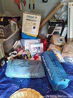 Two Fisher Price bags with varied sizes and blue color tones, Cosco box, and other items placed on a blue sheet on the floor.