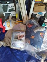 Shows three folded throws and one packaged heated blanket in a cluttered space