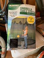 Full box showing Ideaworks Umbrella Table Screen with mesh enclosure and zippered door, model fits up to 9 feet diameter umbrella tables.