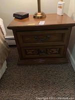Full view of the nightstand next to a bed showing top surface and drawers.