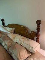 Full view of the wooden queen headboard with carved posts and pillows in front